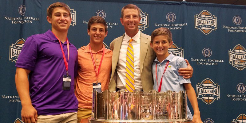 Swinney poses with his sons and just one of the many trophies he's helped win 