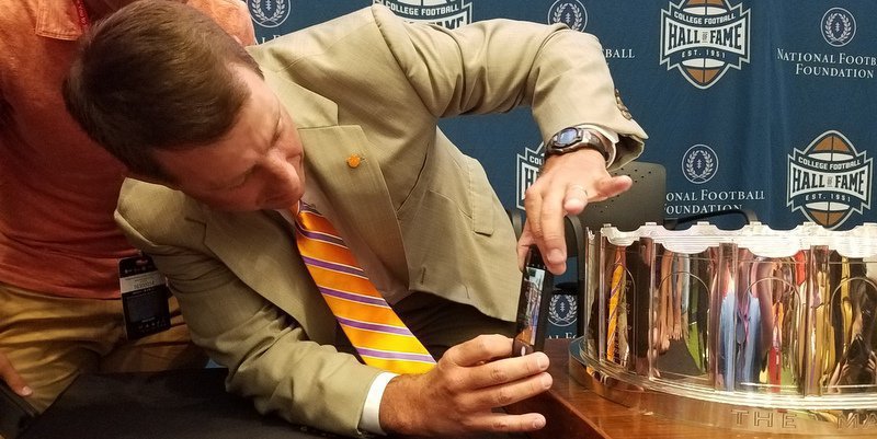 Swinney takes a picture of Clemson's name on the trophy 