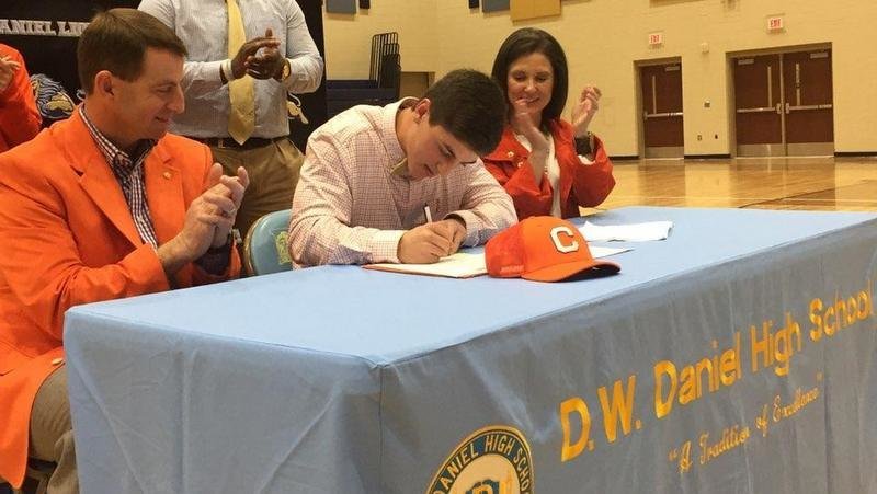 Swinney signs his LOI as his parents look on 